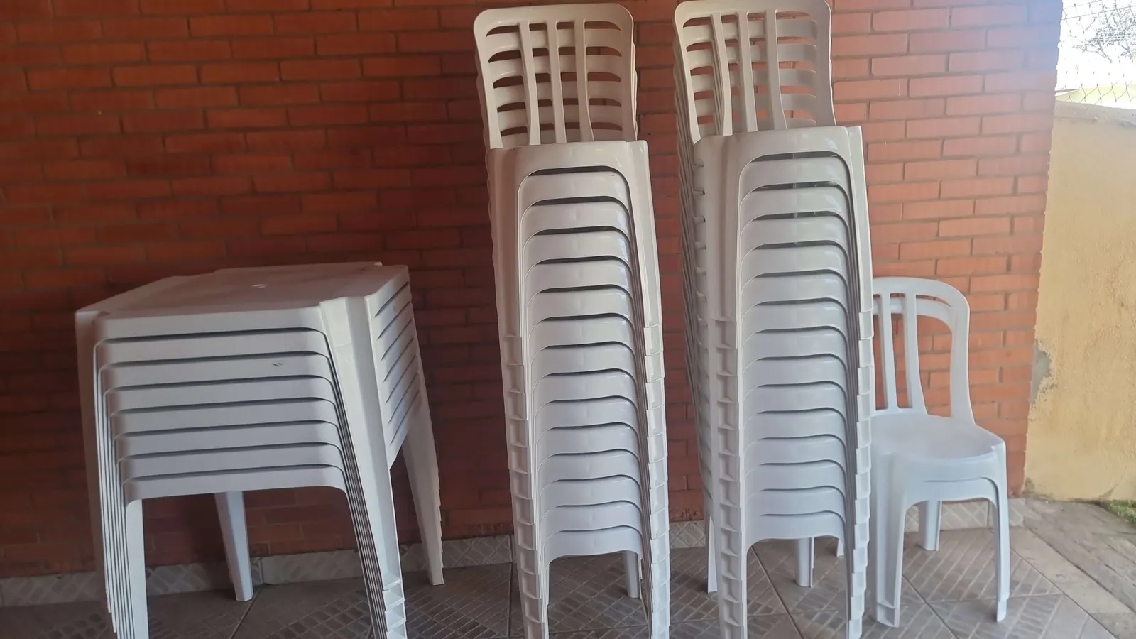 Pilhas de mesas quadradas e cadeiras plásticas brancas